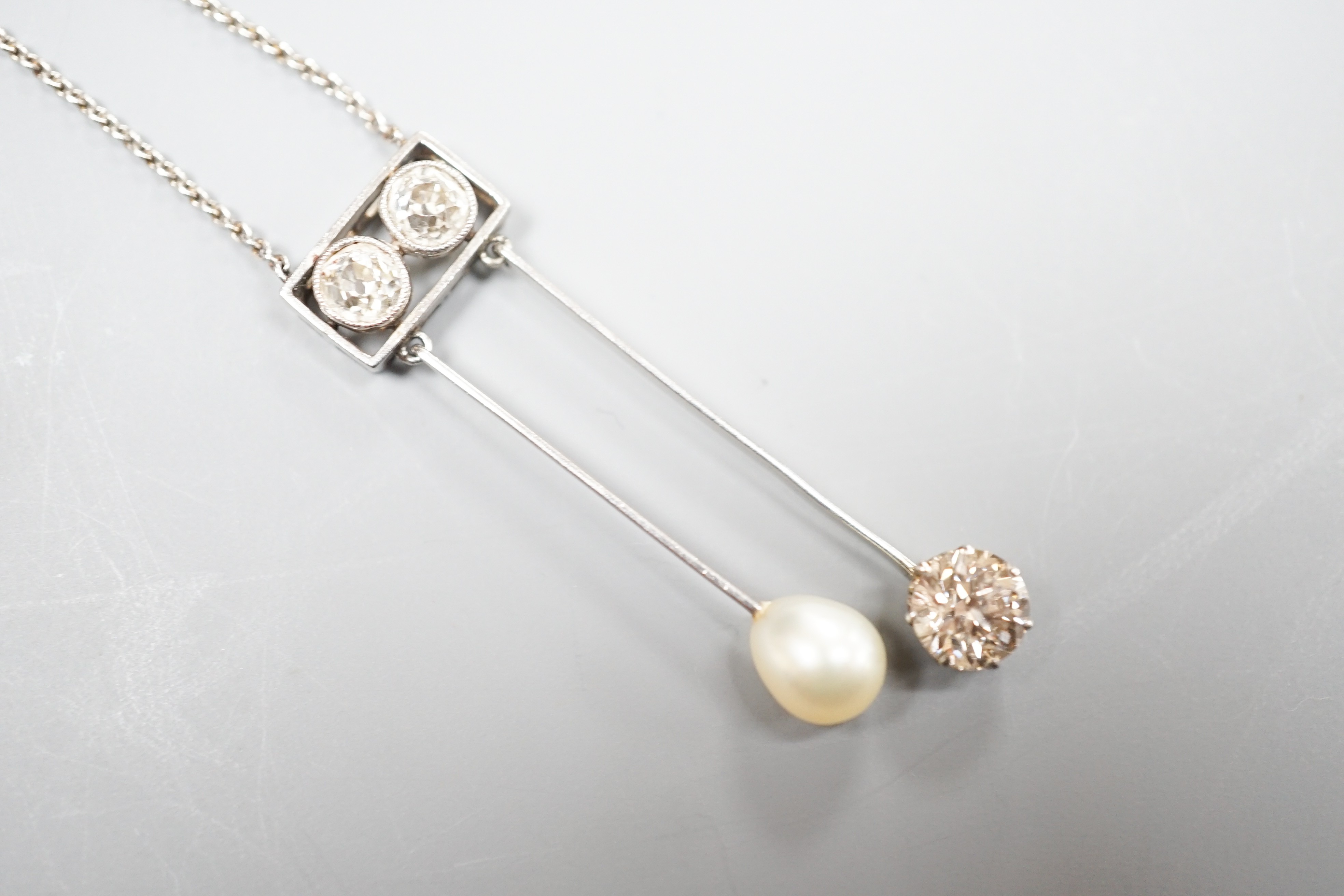 A 1940's white metal (probably platinum), three stone diamond and single stone teardrop shaped pearl set double drop pendant necklace, pendant 39mm, chain 41cm, gross weight 5.9 grams.